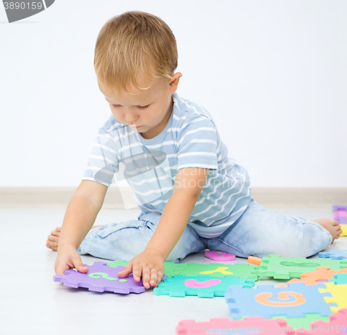 Image of Little boy is putting together a big puzzle