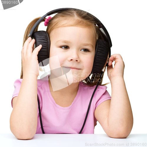 Image of Little girl is enjoying music using headphones