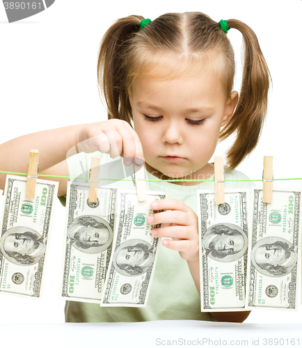 Image of Cute little girl is playing with paper money