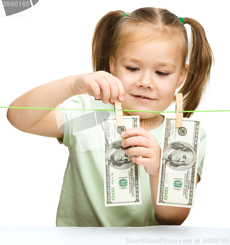 Image of Cute little girl is playing with paper money