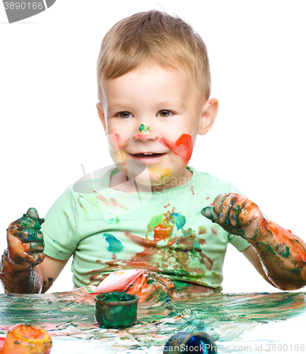 Image of Little boy is playing with paints