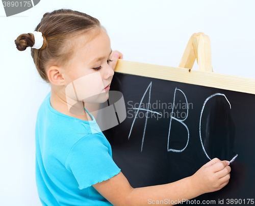 Image of Little girl is writing on a blackboard