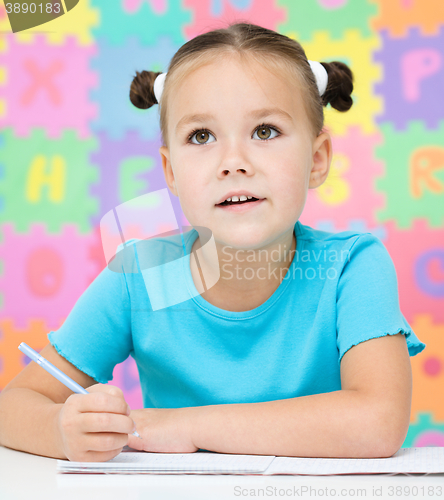 Image of Little girl is writing using a pen