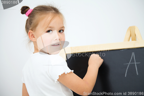 Image of Little girl is writing on a blackboard