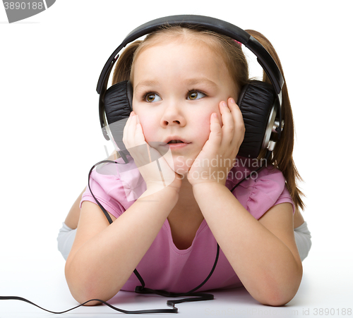 Image of Cute little girl enjoying music using headphones