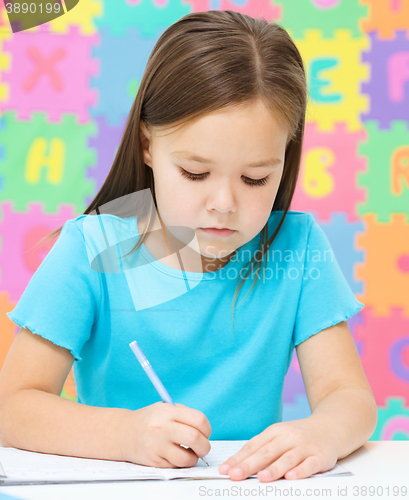 Image of Little girl is writing using a pen