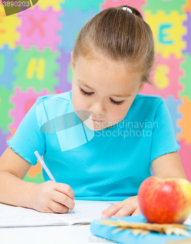 Image of Little girl is writing using a pen