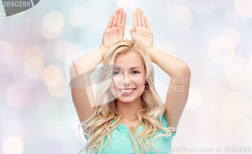 Image of happy smiling young woman making bunny ears