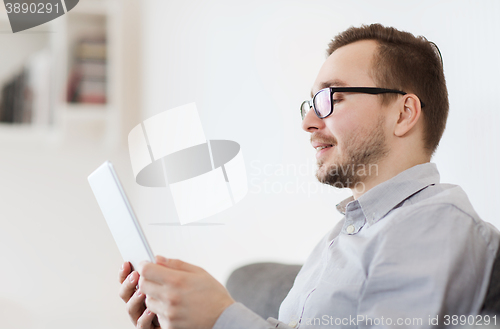 Image of smiling man working with tablet pc at home