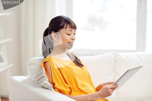 Image of happy young asian woman with tablet pc at home