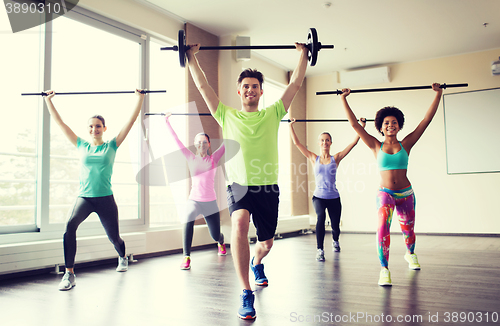 Image of group of people exercising with bars in gym