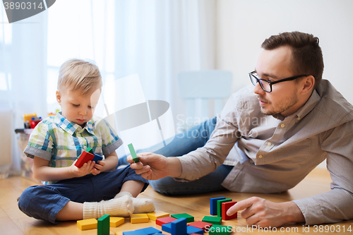 Image of father and son playing with toy blocks at home