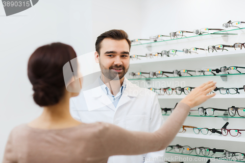 Image of woman showing glasses to optician at optics store