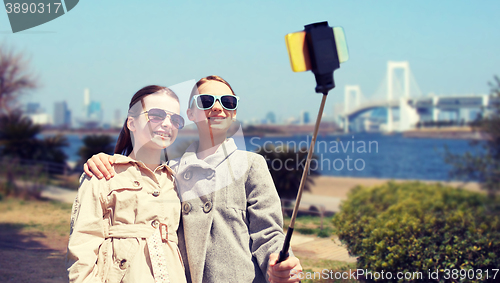 Image of happy girls with smartphone selfie stick in tokyo