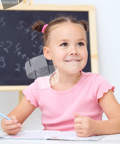 Image of Little girl is writing using a pen