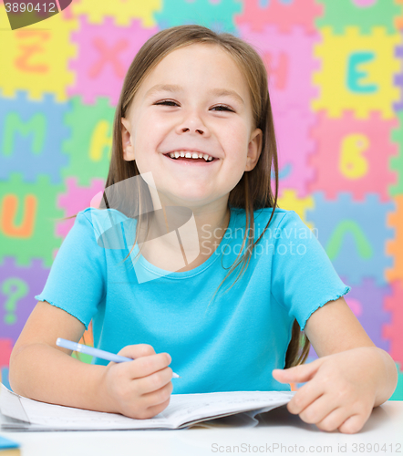 Image of Little girl is writing using a pen