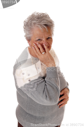 Image of Older senior woman holding hand on face.