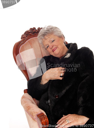 Image of Senior woman sitting in pink armchair.