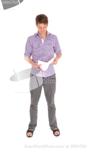 Image of Man standing reading some papers.