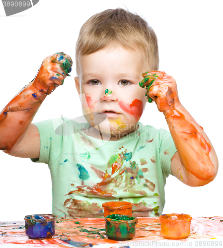 Image of Little boy is playing with paints