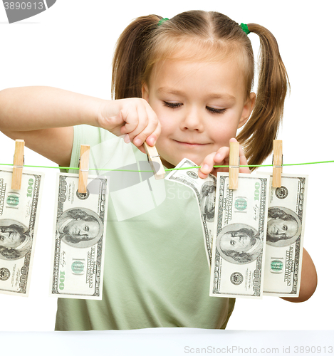 Image of Cute little girl is playing with paper money
