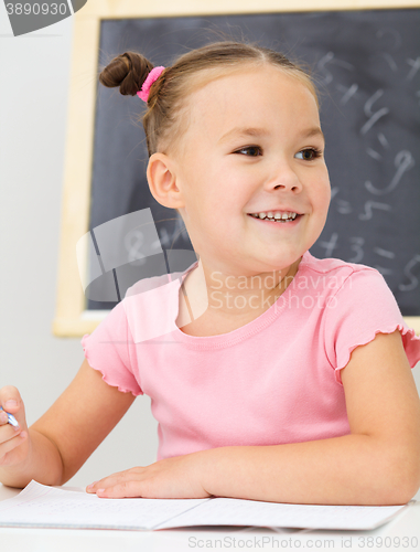 Image of Little girl is writing using a pen