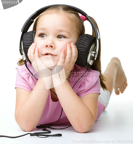 Image of Cute little girl enjoying music using headphones