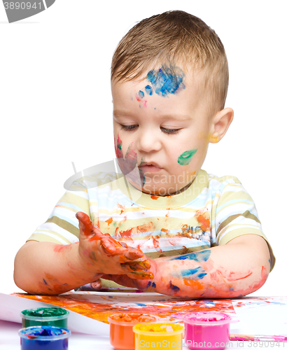 Image of Little boy is playing with paints