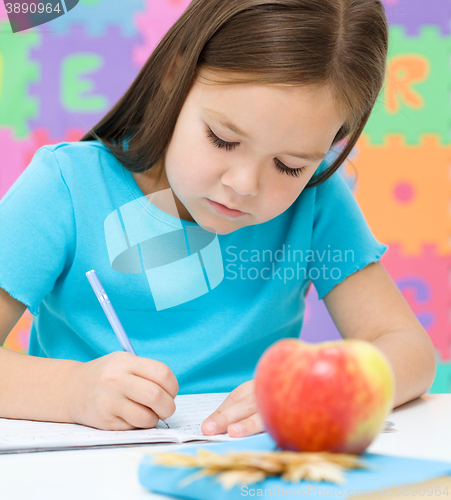 Image of Little girl is writing using a pen