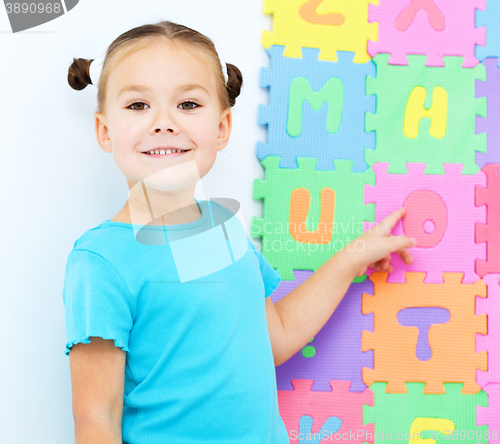 Image of Little girl is pointing at letter O on alphabet