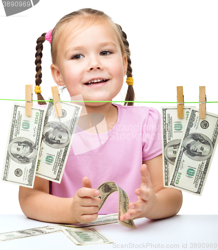 Image of Cute little girl is playing with paper money