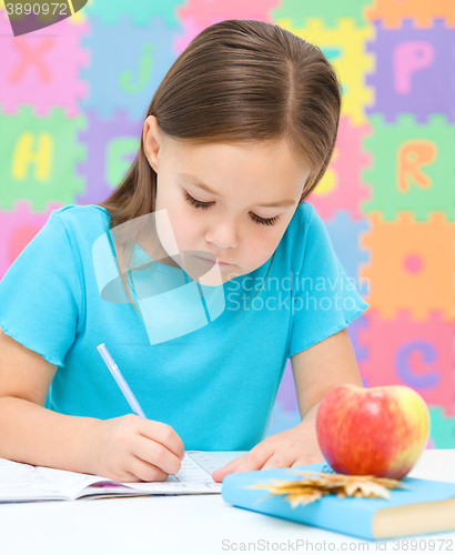 Image of Little girl is writing using a pen