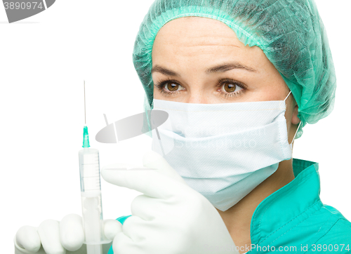 Image of Young nurse is preparing syringe for injection