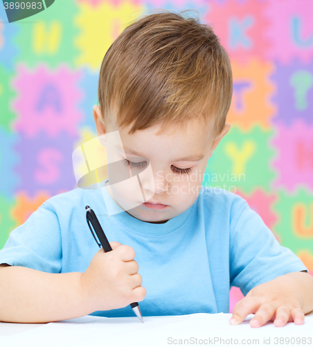 Image of Little boy is writing on his copybook