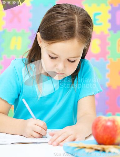 Image of Little girl is writing using a pen