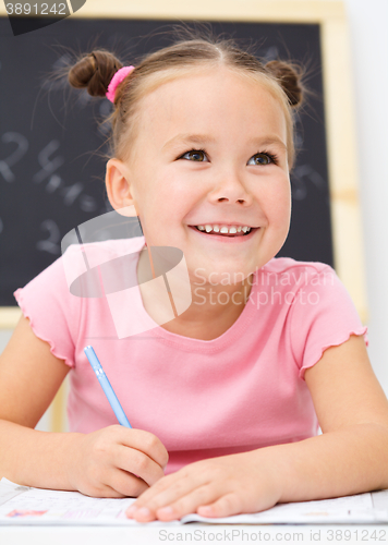 Image of Little girl is writing using a pen