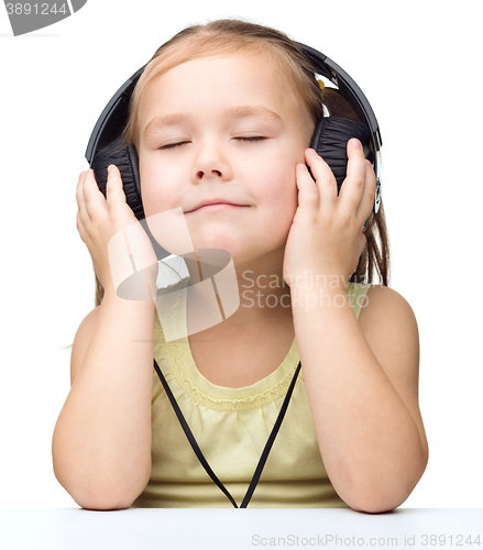 Image of Little girl is enjoying music using headphones