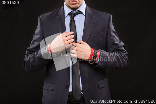 Image of man in a business suit with leather bound with handcuffs. sex Toys