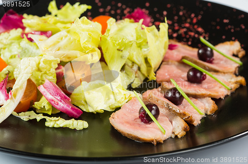 Image of grilled meat with lettuce. on black plate