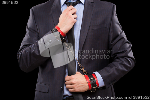 Image of man in a business suit with leather bound. handcuffs. sex Toys