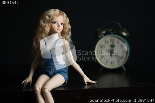 Image of doll on the background of the old clock.