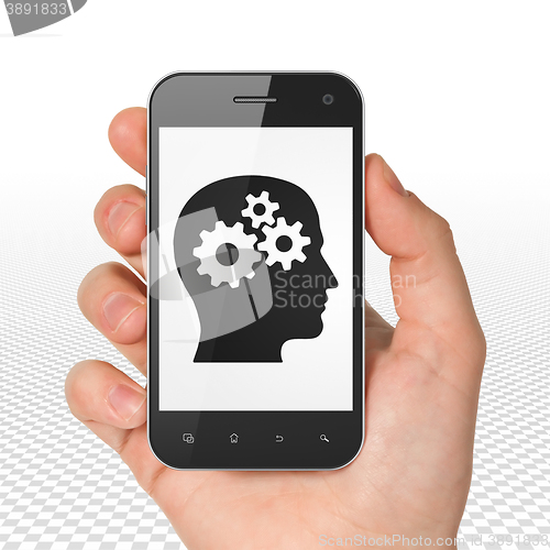 Image of Business concept: Hand Holding Smartphone with Head With Gears on display