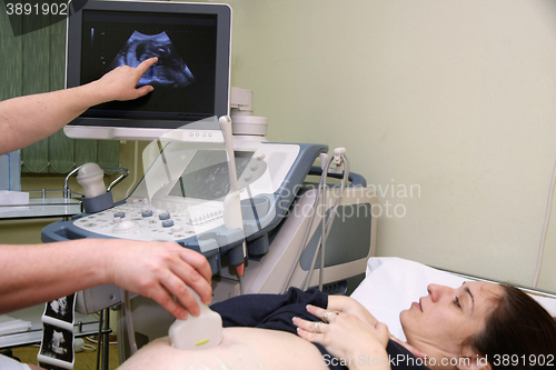 Image of Pregnant woman and doctor hand\'s with ultrasound equipment durin