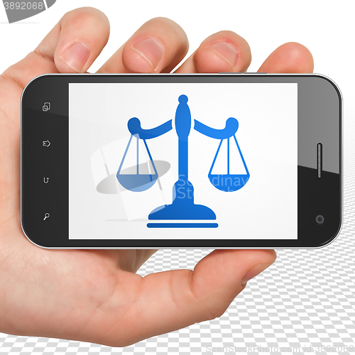 Image of Law concept: Hand Holding Smartphone with Scales on display