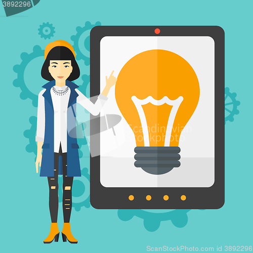 Image of Woman pointing at tablet computer with light bulb on screen.