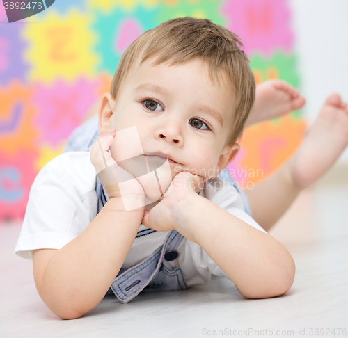 Image of Little boy is laying on a floor
