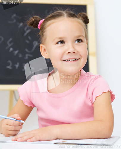 Image of Little girl is writing using a pen