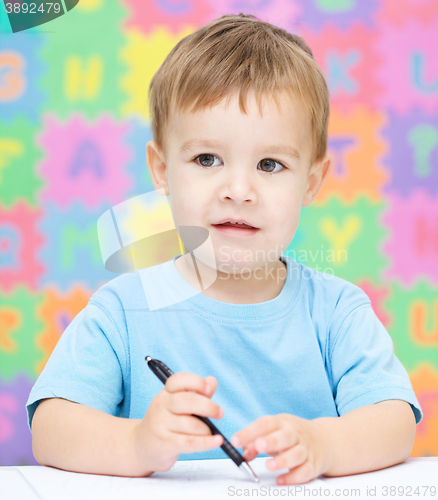 Image of Little boy is writing on his copybook