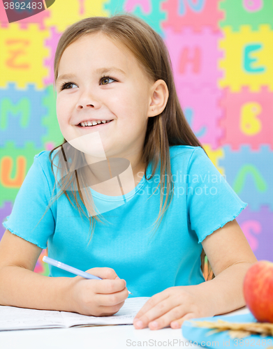 Image of Little girl is writing using a pen