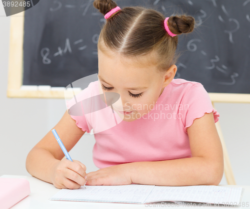 Image of Little girl is writing using a pen